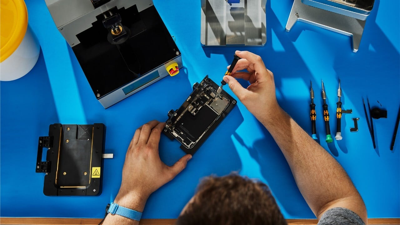 Technician repairing a phone on a blue bench
